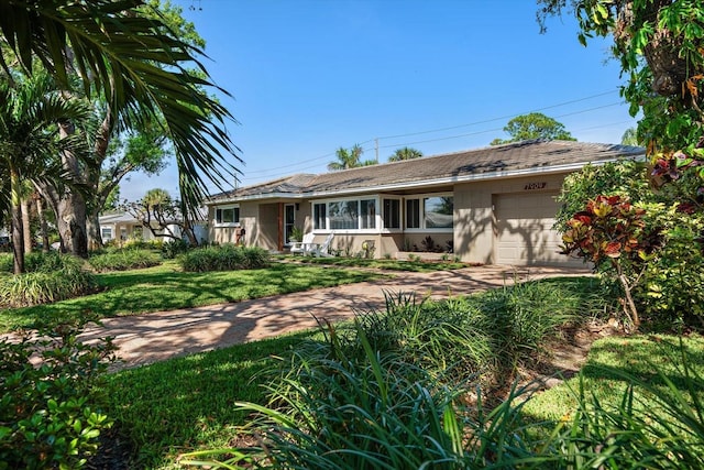 single story home with an attached garage, a front lawn, and concrete driveway