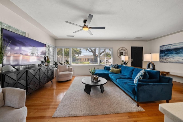 living area with visible vents, light wood-style floors, ceiling fan, and a textured ceiling