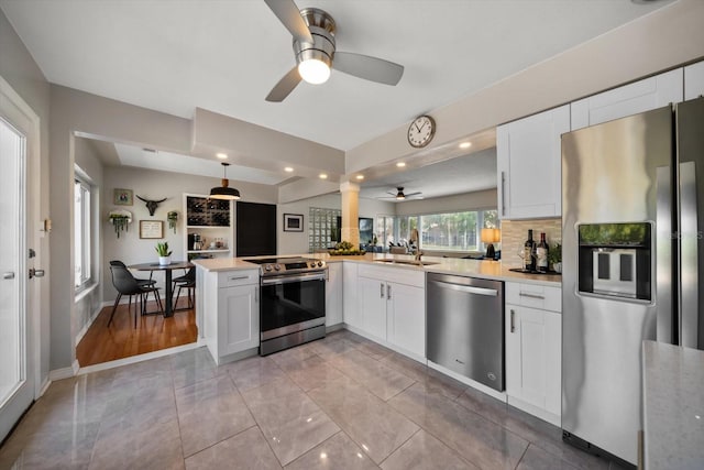 kitchen featuring light countertops, stainless steel appliances, a sink, ceiling fan, and a peninsula