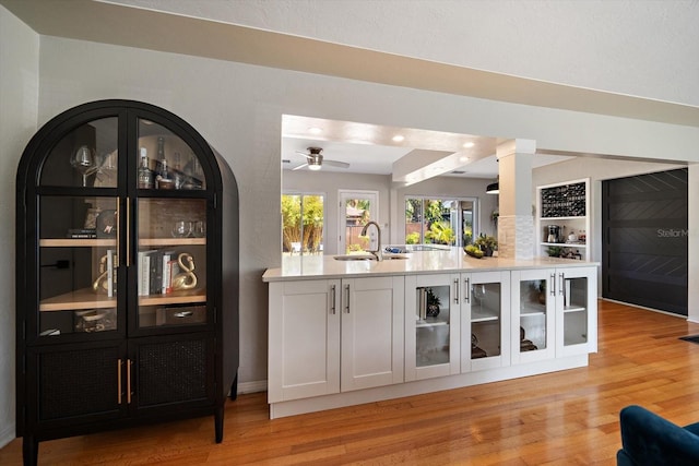 bar featuring light wood-style flooring, a sink, and ceiling fan