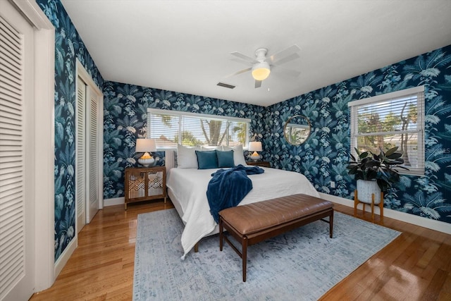 bedroom featuring baseboards, wallpapered walls, and light wood-style flooring
