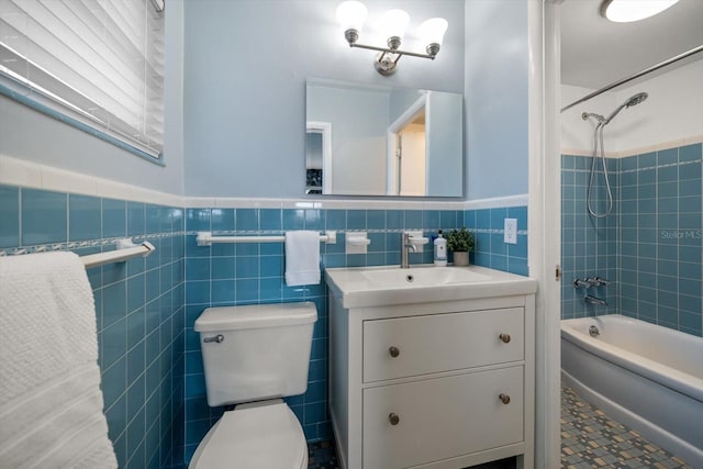 full bathroom featuring toilet, vanity, shower / bath combination, wainscoting, and tile walls
