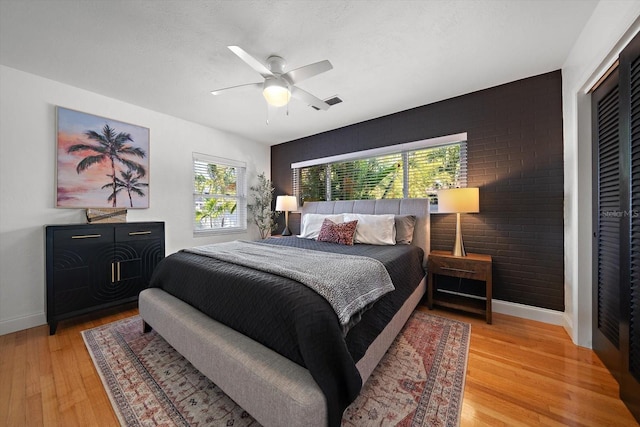 bedroom with baseboards, visible vents, light wood-style flooring, and ceiling fan