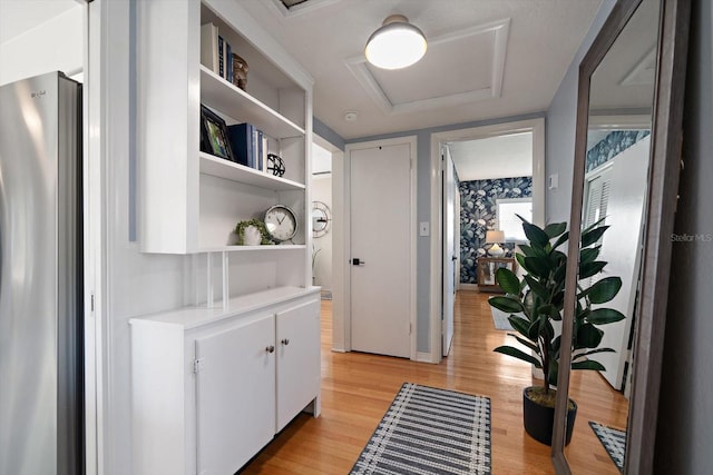 hall featuring baseboards, light wood-style flooring, and attic access
