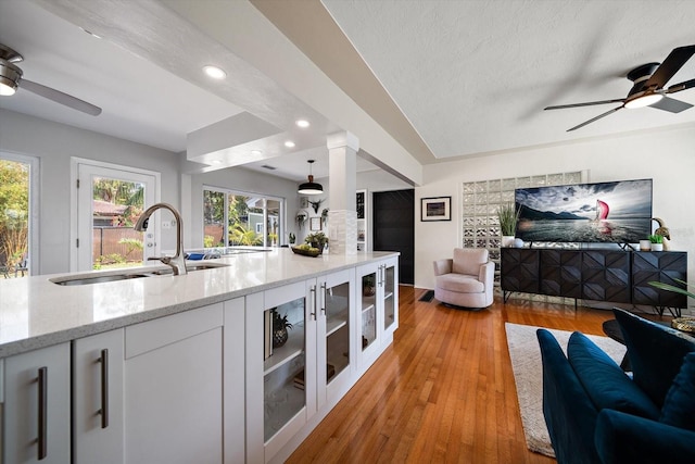 kitchen featuring open floor plan, white cabinets, a sink, and ceiling fan