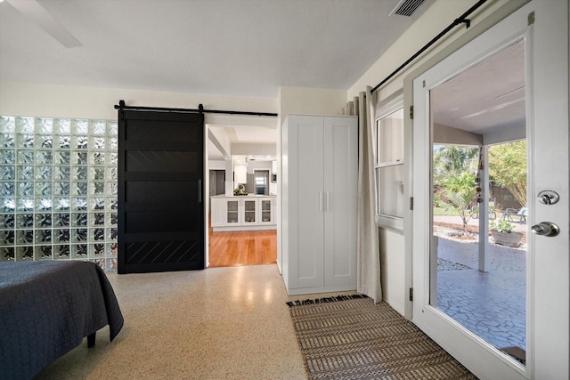 bedroom featuring a barn door, access to exterior, visible vents, and speckled floor