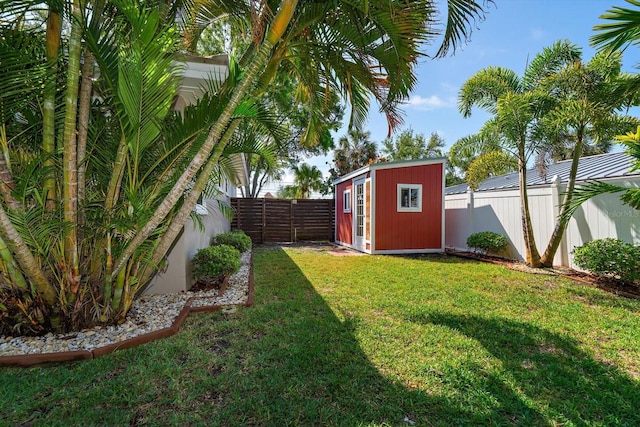 view of yard featuring a fenced backyard, a storage unit, and an outdoor structure