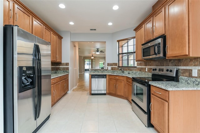 505 Millifiora Ln, Kissimmee, FL 34759 - kitchen with stainless steel appliances, a sink, decorative backsplash, light stone countertops, and brown cabinetry