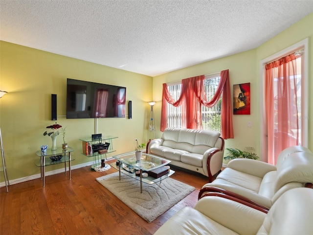 living area featuring a textured ceiling, wood finished floors, and baseboards