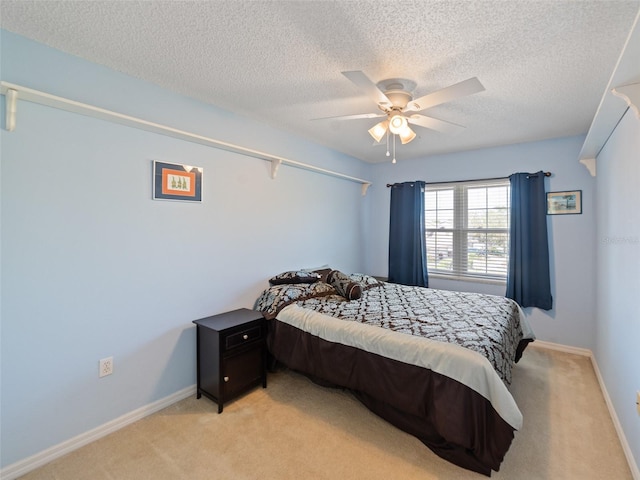 bedroom with baseboards, a ceiling fan, light colored carpet, and a textured ceiling