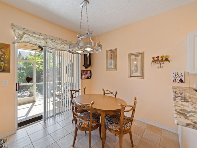 dining room featuring light tile patterned floors, a textured ceiling, and baseboards