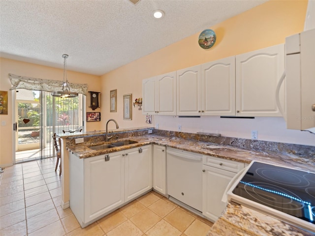 kitchen with white appliances, a peninsula, a textured ceiling, white cabinets, and a sink