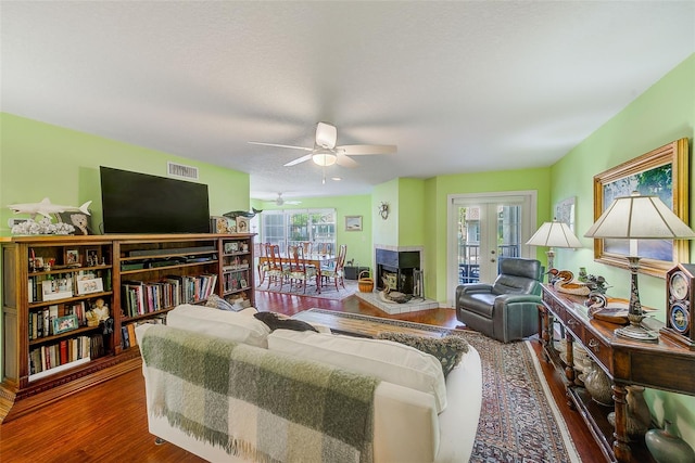 living area with french doors, visible vents, a ceiling fan, and wood finished floors