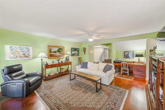living area featuring a textured ceiling, wood finished floors, ceiling fan, and stairway