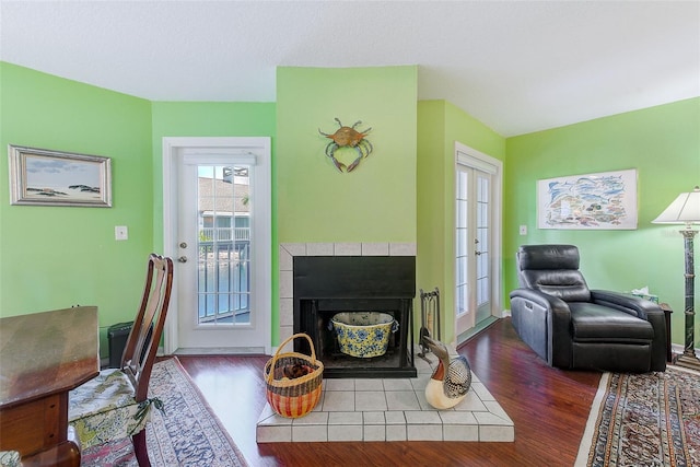 living room featuring baseboards, a tile fireplace, and wood finished floors