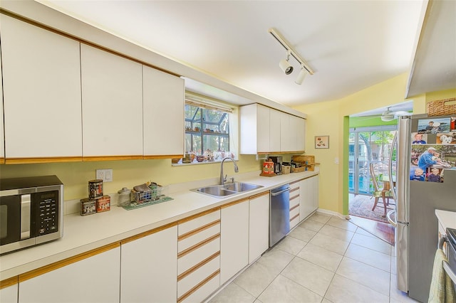 kitchen featuring light tile patterned floors, white cabinets, appliances with stainless steel finishes, light countertops, and a sink