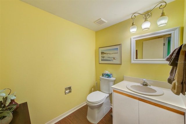 half bath featuring vanity, baseboards, toilet, visible vents, and wood finished floors