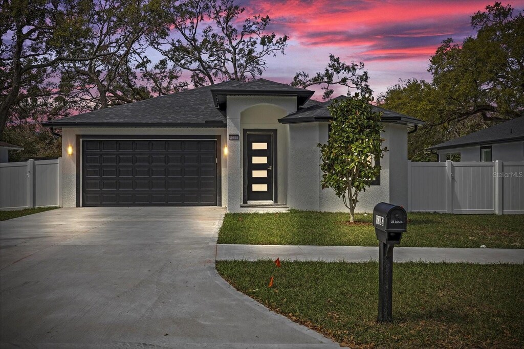 6302 N 39th St, Tampa, FL 33610 - prairie-style house featuring driveway, stucco siding, fence, an attached garage, and a yard