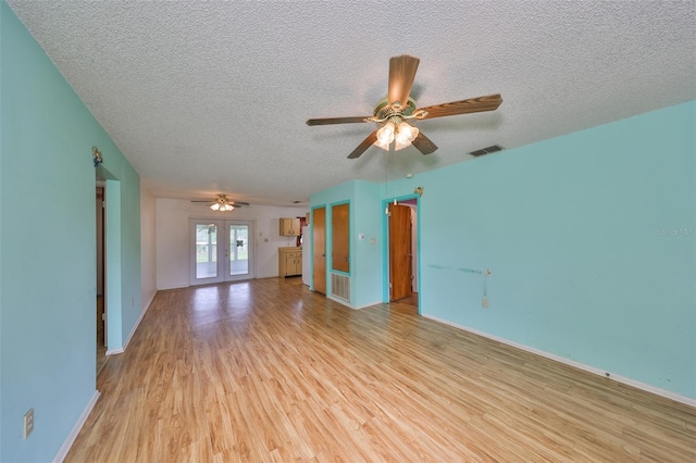 9210 Lehall Sq W, Lakeland, FL 33810 - unfurnished living room with light wood finished floors, a textured ceiling, a ceiling fan, baseboards, and french doors
