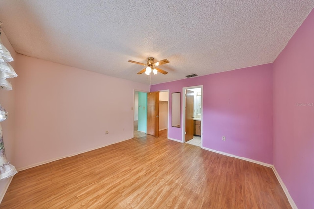 9210 Lehall Sq W, Lakeland, FL 33810 - unfurnished bedroom featuring light wood-type flooring, baseboards, a textured ceiling, a spacious closet, and connected bathroom