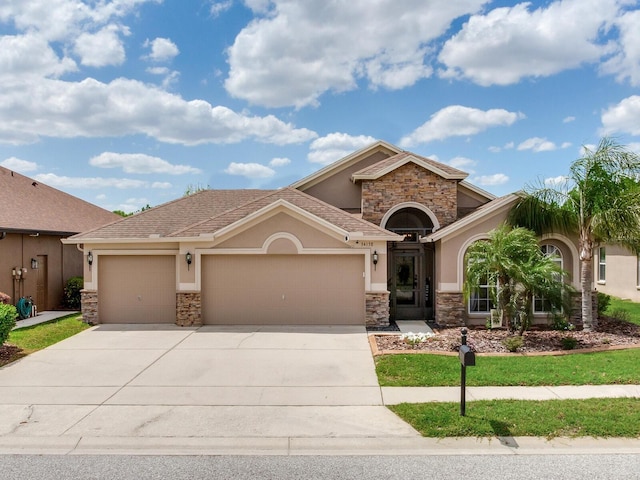 view of front of home with stone siding, stucco siding, driveway, and a garage