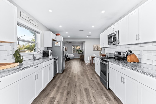 1543 Gentry St, Clearwater, FL 33755 - kitchen featuring decorative backsplash, light stone countertops, white cabinets, a sink, and appliances with stainless steel finishes