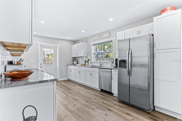 1543 Gentry St, Clearwater, FL 33755 - kitchen featuring light stone countertops, light wood-type flooring, a sink, stainless steel appliances, and white cabinetry