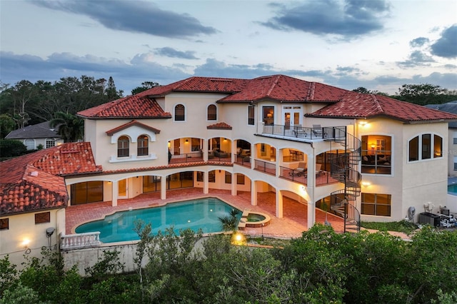 back of property with a tile roof, stucco siding, stairs, a balcony, and a patio area