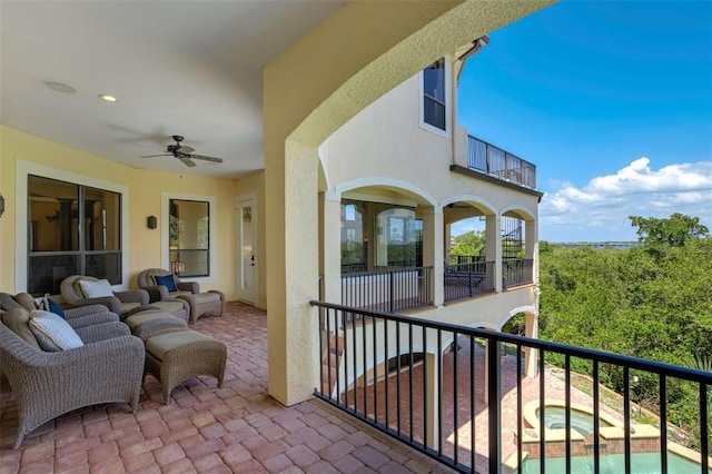 view of patio / terrace with a balcony, an in ground hot tub, and a ceiling fan