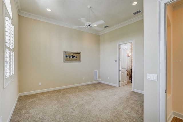 spare room with carpet, ornamental molding, visible vents, and a ceiling fan
