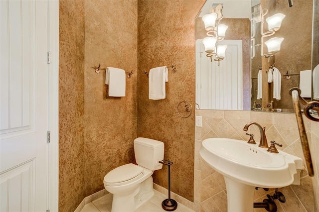 bathroom featuring toilet, a sink, tile patterned flooring, baseboards, and decorative backsplash