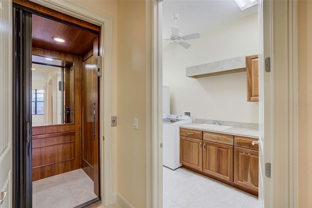 interior space with light tile patterned flooring, a sink, a ceiling fan, elevator, and washer / clothes dryer