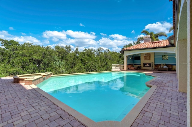 view of pool featuring exterior fireplace, a pool with connected hot tub, and a patio