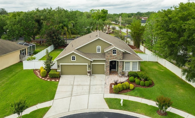 view of front of property with driveway, a fenced backyard, stone siding, and a front lawn