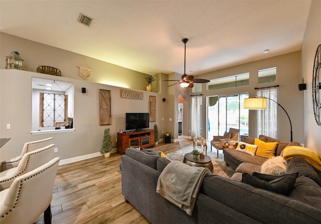 living room with light wood finished floors, baseboards, a ceiling fan, and visible vents