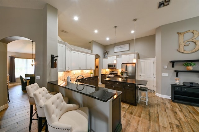 kitchen with arched walkways, a sink, dark countertops, and stainless steel appliances