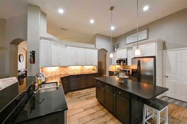 kitchen featuring arched walkways, appliances with stainless steel finishes, a sink, and wood tiled floor