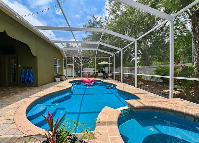 view of pool featuring a patio, a fenced backyard, a pool with connected hot tub, and glass enclosure