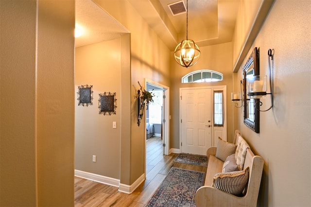 entrance foyer featuring visible vents, baseboards, light wood finished floors, and an inviting chandelier