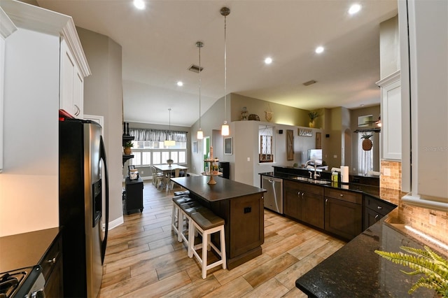 kitchen with visible vents, hanging light fixtures, a kitchen breakfast bar, stainless steel appliances, and light wood-style flooring