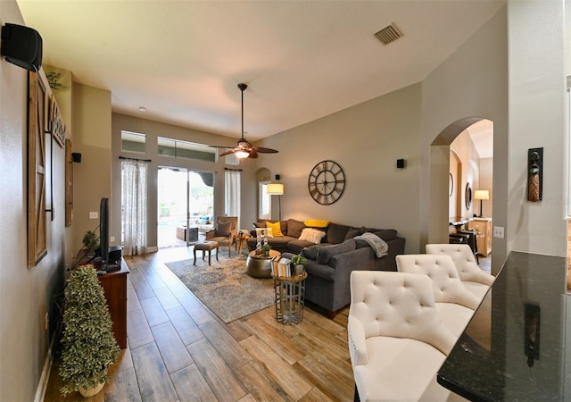 living room featuring a high ceiling, visible vents, ceiling fan, arched walkways, and wood finished floors