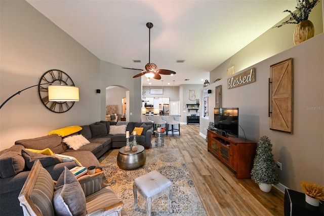living room with baseboards, light wood-style flooring, visible vents, ceiling fan, and arched walkways