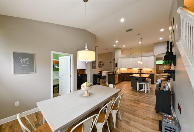 dining area with light wood-type flooring, baseboards, recessed lighting, visible vents, and lofted ceiling