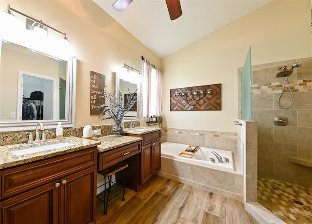full bath featuring vaulted ceiling, tiled shower, a bath, ceiling fan, and a sink