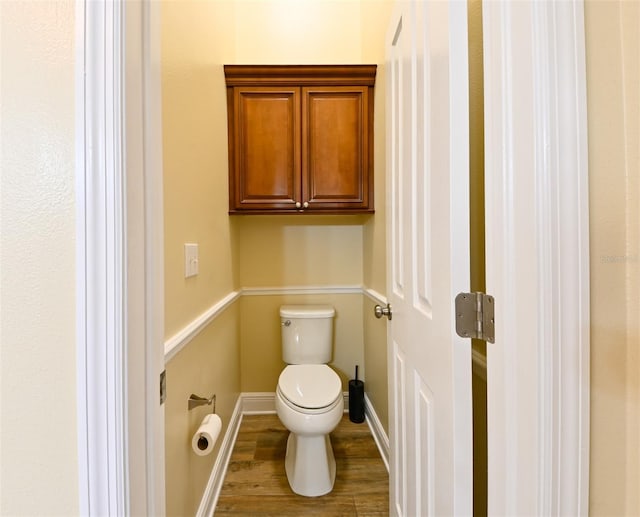 bathroom with toilet, wood finished floors, and baseboards