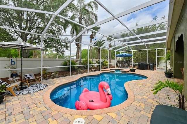 view of pool featuring a patio, a fenced backyard, a pool with connected hot tub, and glass enclosure
