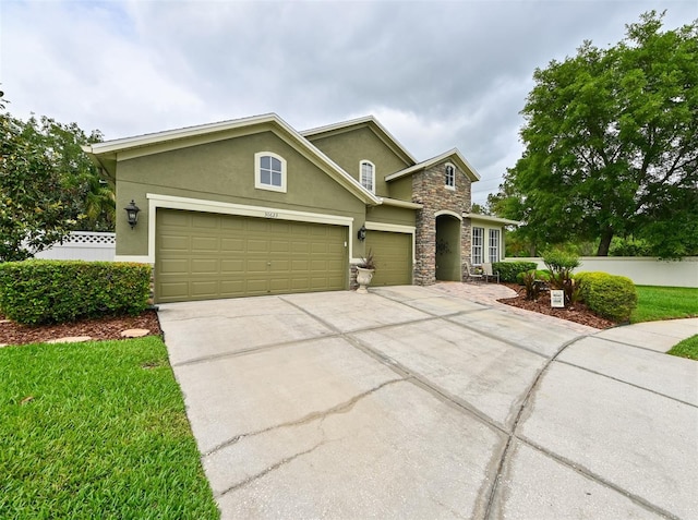 traditional-style house with concrete driveway, stucco siding, stone siding, and an attached garage