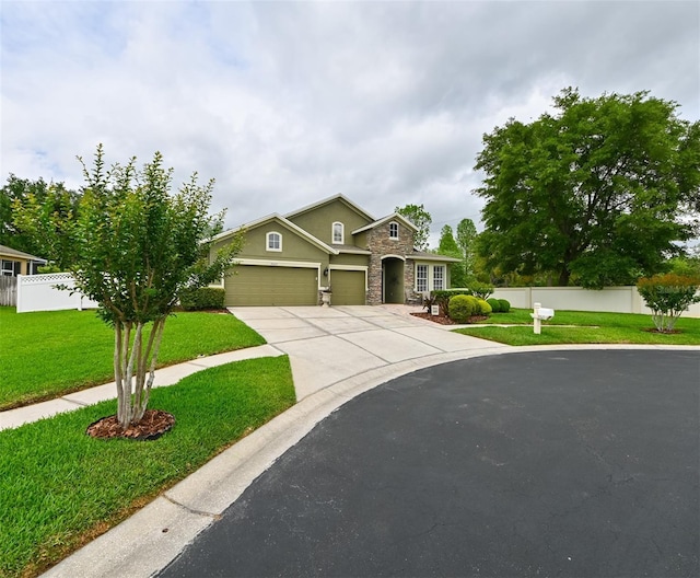 traditional-style home with a garage, stone siding, fence, a front lawn, and concrete driveway