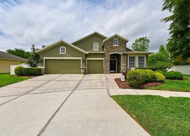 traditional-style house with stone siding, a garage, fence, concrete driveway, and stucco siding