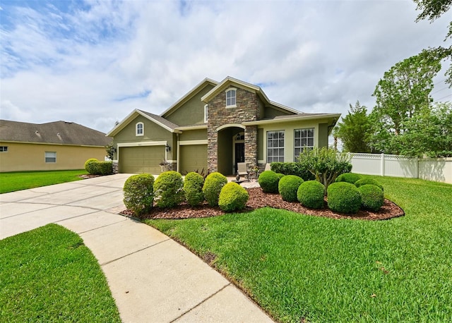 craftsman inspired home featuring concrete driveway, stucco siding, stone siding, a front lawn, and fence